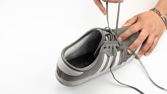 A person removing the laces from their tennis shoes before machine washing