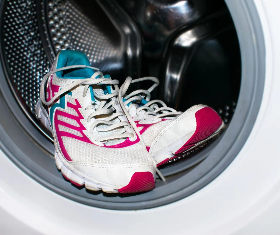 Tennis shoes being placed inside a washing machine, ready for a gentle wash